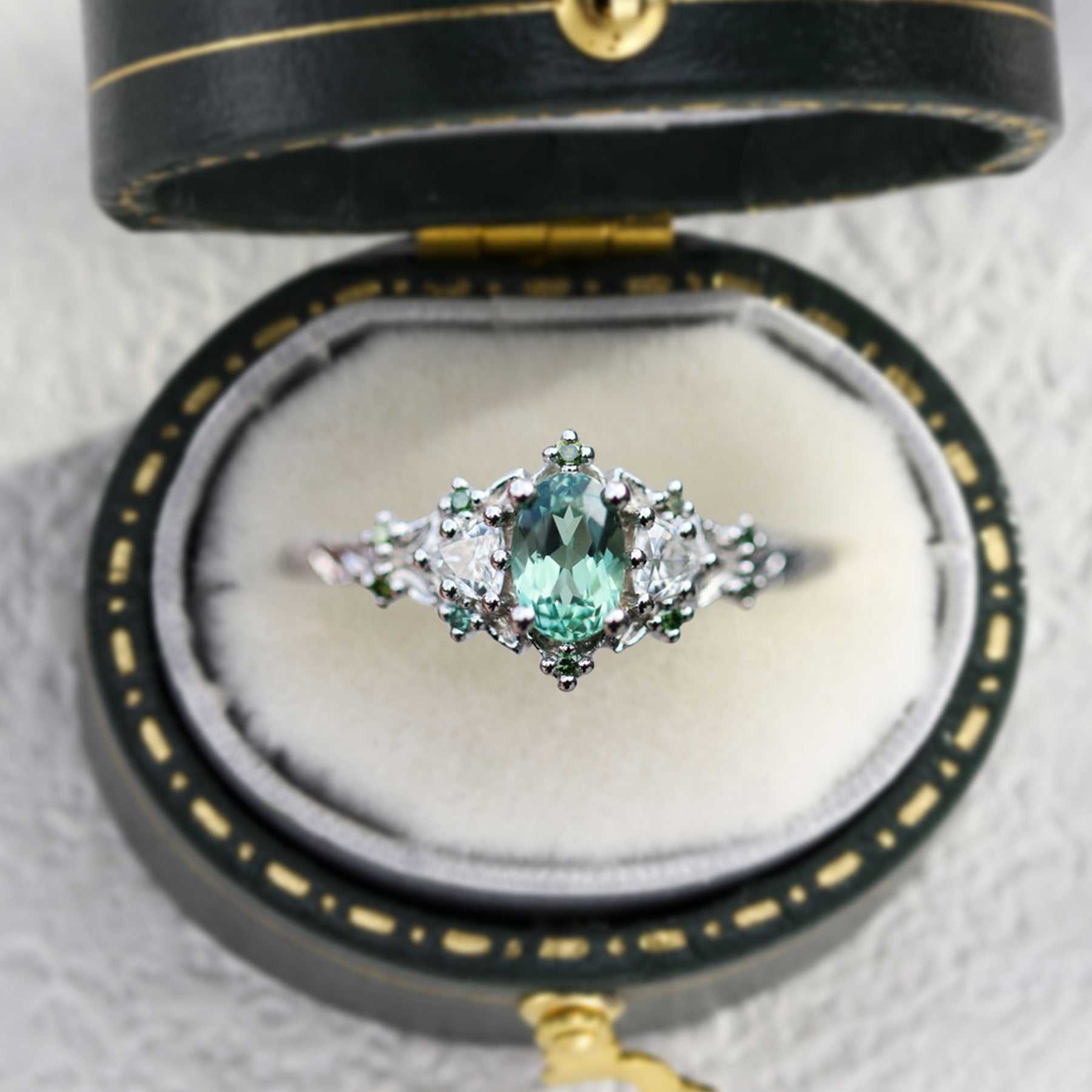 Dulawen three-stone engagement ring with oval sapphire and trillion moissanite side stones in elegant black velvet box