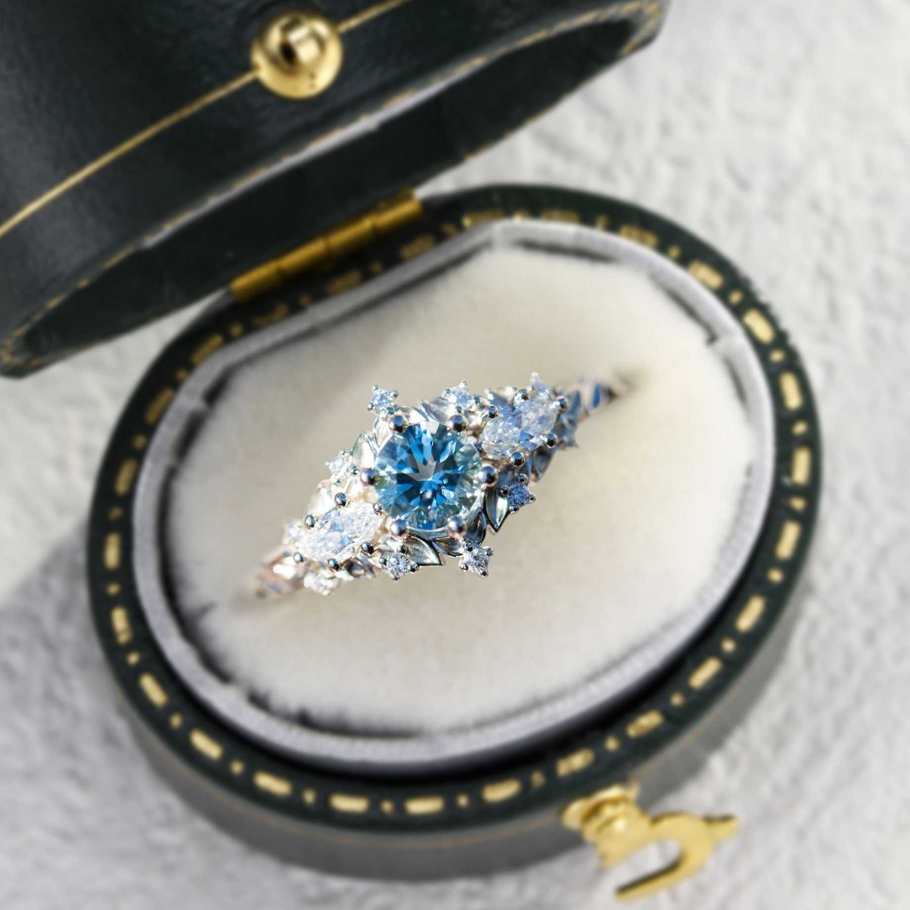 Nelawen three-stone engagement ring with 6mm aquamarine center and moissanite side stones in black velvet box