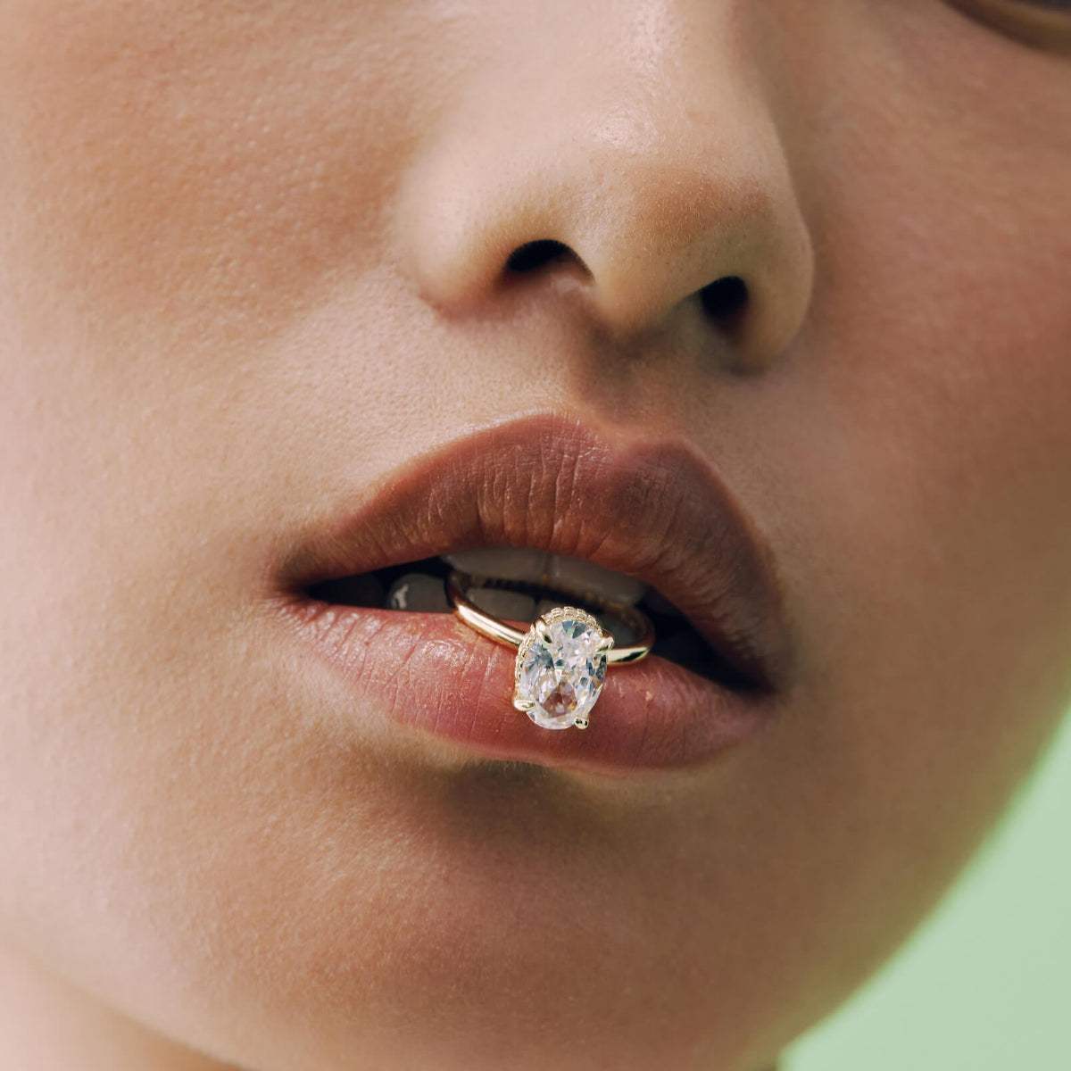 Nolindra solitaire engagement ring with oval Moissanite and pavé hidden halo on lips close-up