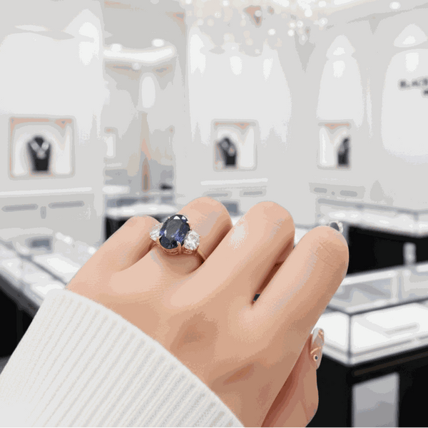 Quaeriel ring with 3.5 carat oval-cut blue sapphire and two sparkling side stones on hand in jewelry store