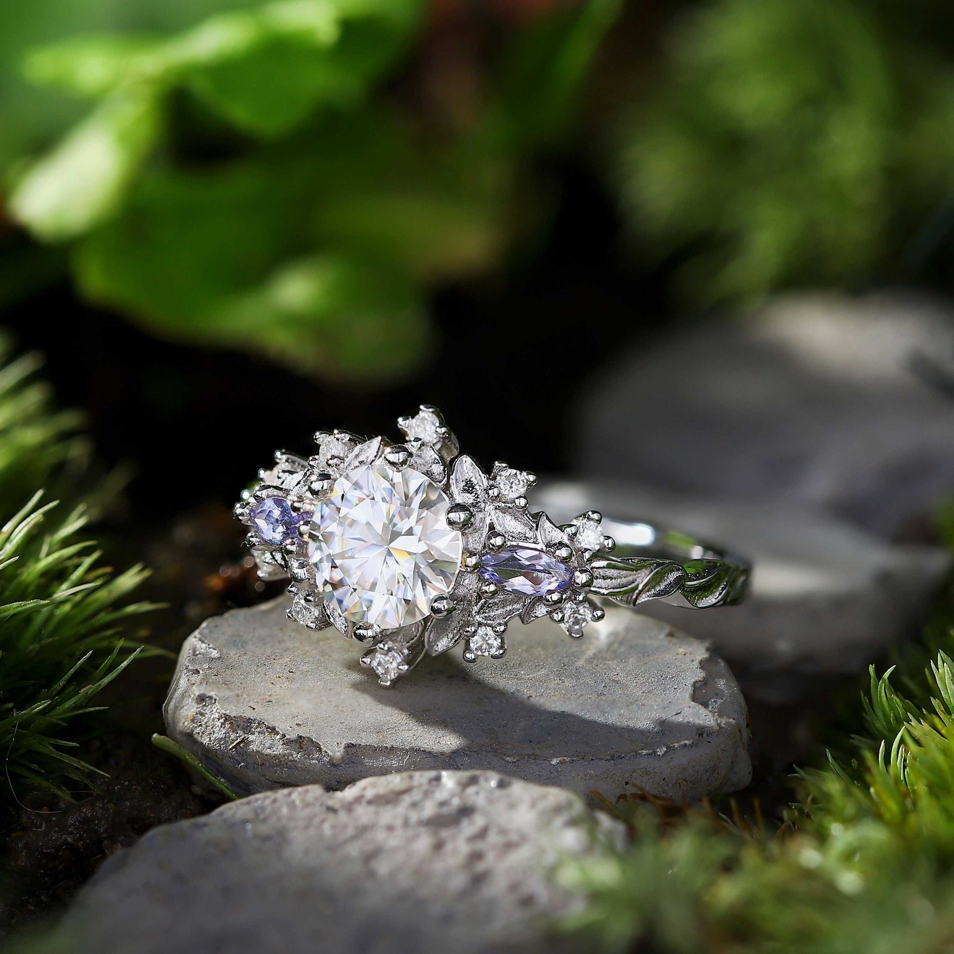 Rilaswen ring with round moissanite center stone and two smaller accent stones on nature background