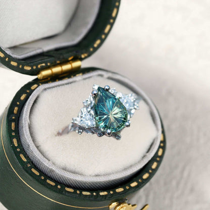 Garaniel solitaire engagement ring with pear-shaped sapphire and moissanite side stones in green velvet box