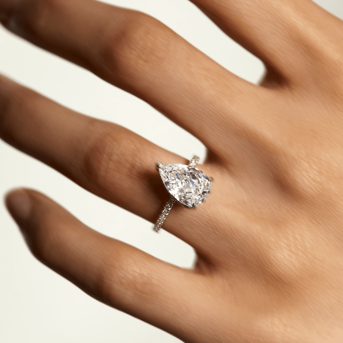 Kylariel pear-shaped moissanite solitaire engagement ring with half pavé band and hidden halo on hand