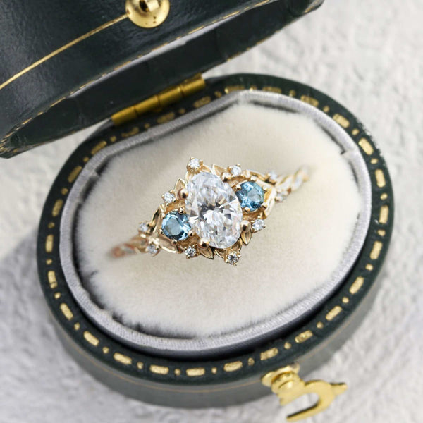 Vaelawen three-stone engagement ring with 4 ct oval moissanite center stone and blue side stones in a vintage box