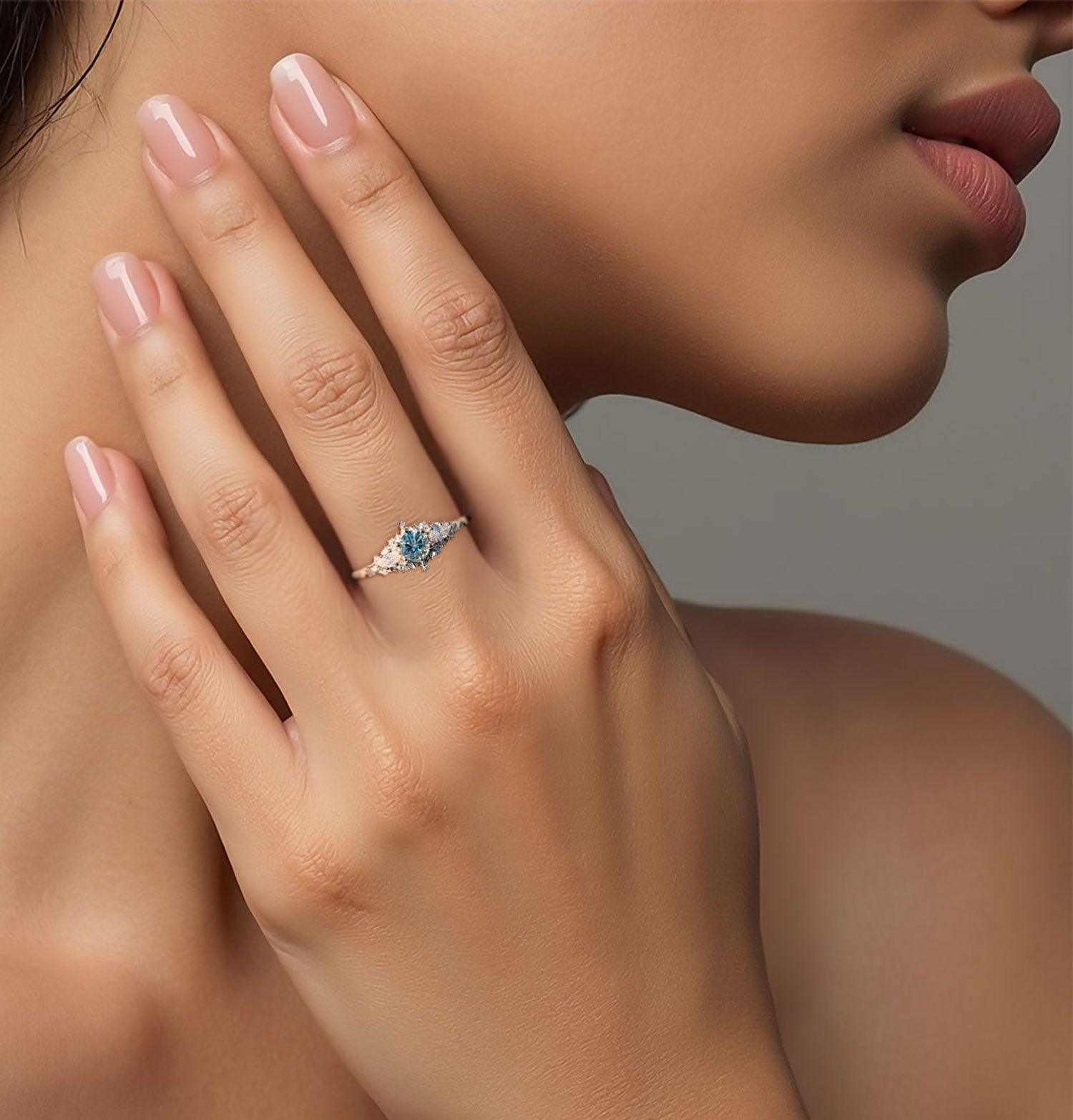 Nelawen three-stone engagement ring with 6mm round aquamarine center and moissanite side stones on hand