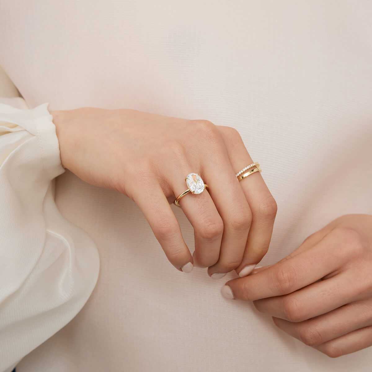 Close-up of hand wearing Pherinwen Deus Ring with oval-cut 3-carat moissanite solitaire on gold band