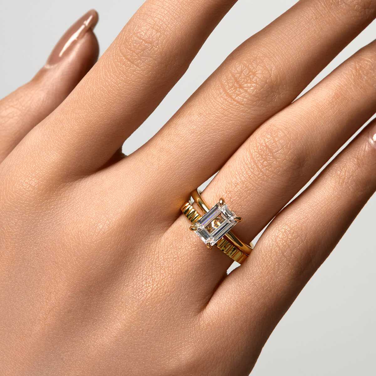 Emera Ring with emerald-shaped moissanite stone on hand in sleek plain band