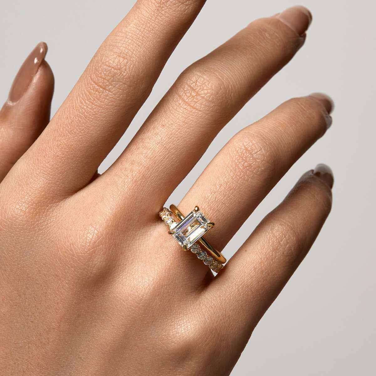 Emera Ring with emerald-shaped moissanite stone on hand with sleek gold band