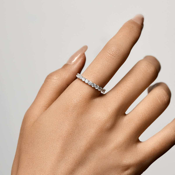Petite brilliant round band eternity ring with sparkling moissanite stones on hand