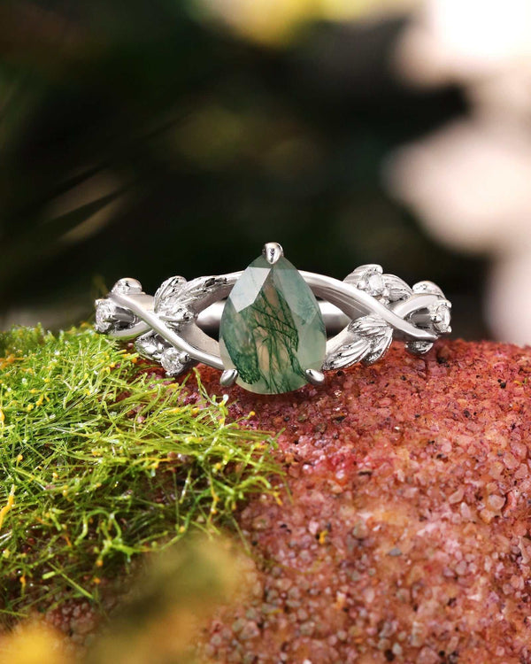 Quistwen solitaire engagement ring with pear-shaped moss agate and moissanite side stones on split shank band with leaf motif