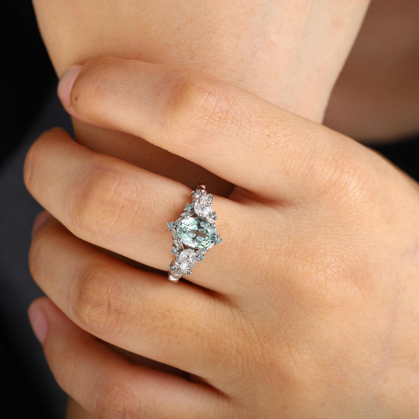 Tyranel engagement ring with 6x4mm oval sapphire and marquise round moissanite halo on finger