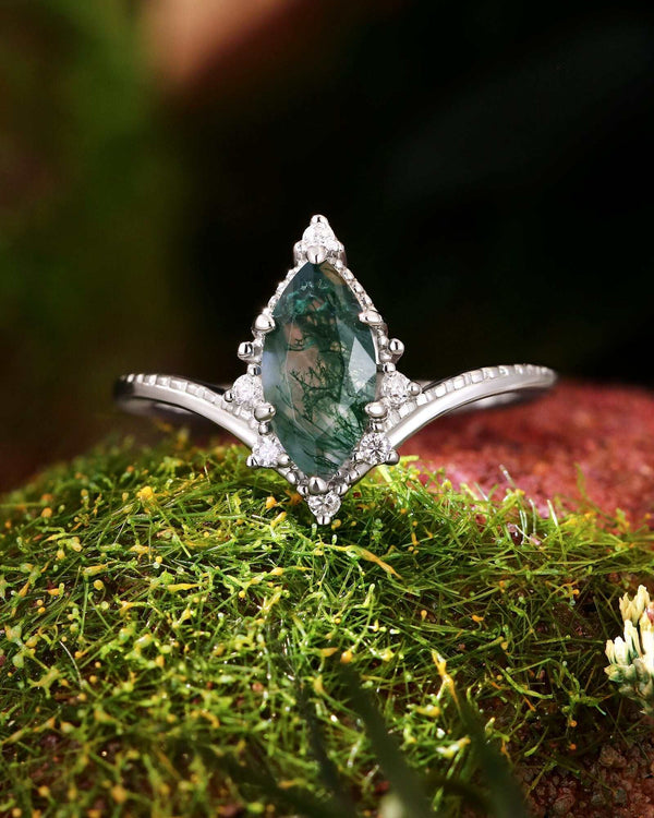 Tesariel marquise moss agate engagement ring with moissanite accents on moss background