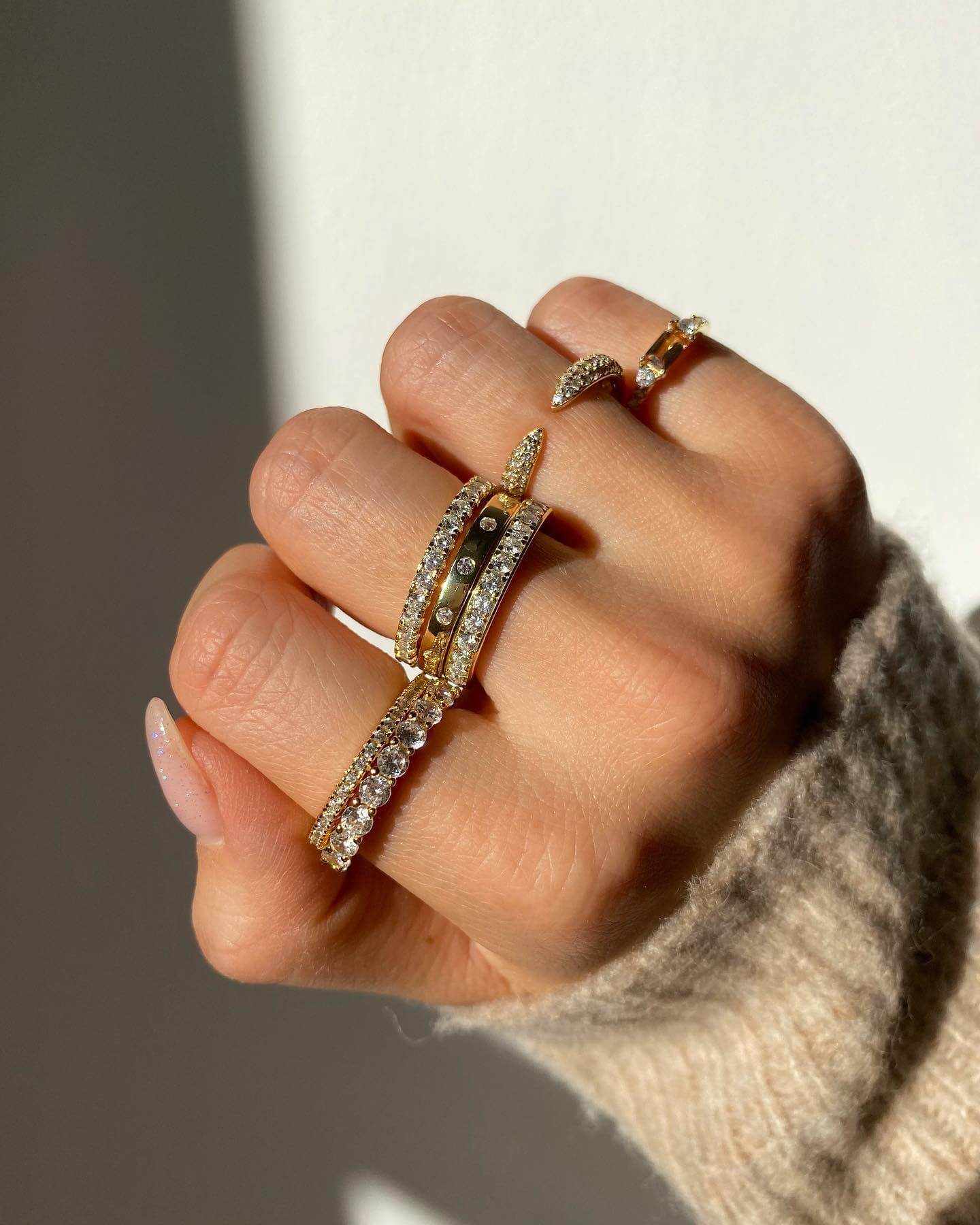 Close-up of hand wearing Perawen Selene eternity ring with sparkling moissanite stones on gold band.
