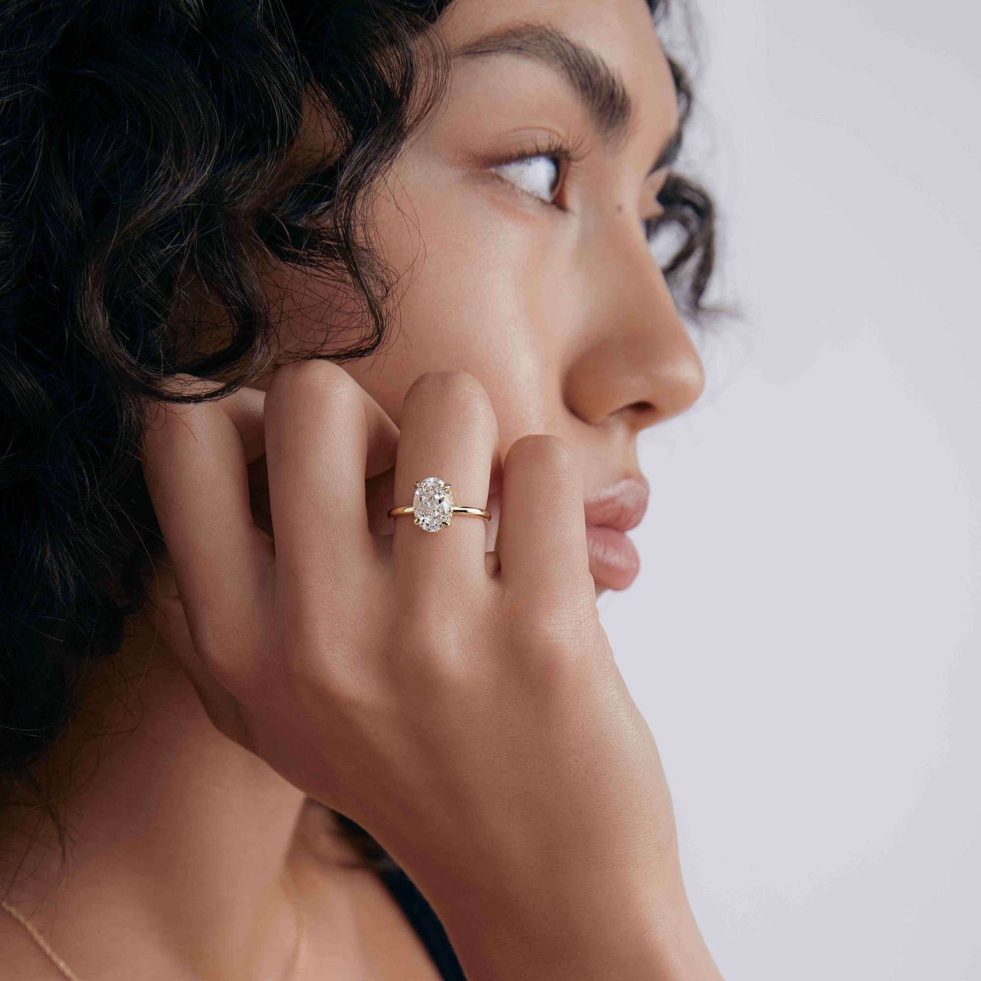 Nolindra solitaire engagement ring with oval Moissanite and pavé hidden halo on model's hand