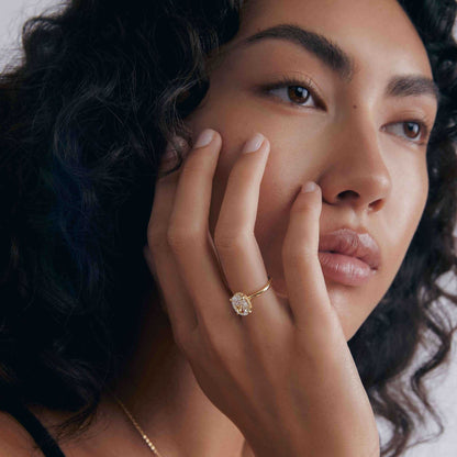 Close-up of woman wearing Nolindra solitaire engagement ring with oval Moissanite and pavé hidden halo on finger