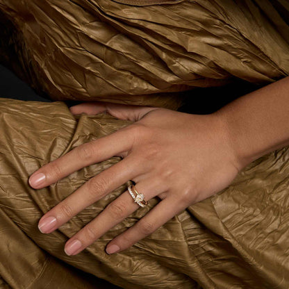 Selene eternity ring with petite round moissanite stones on hand against textured gold fabric background