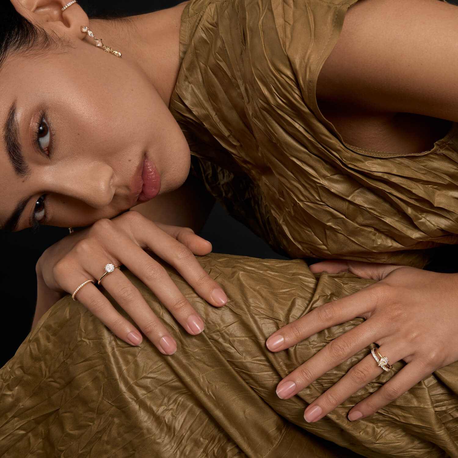 Woman wearing Selene eternity ring with petite round moissanite stones on hand in elegant gold dress