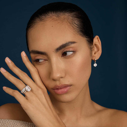 Woman wearing Selene eternity ring with petite round moissanite stones and matching earring on dark background