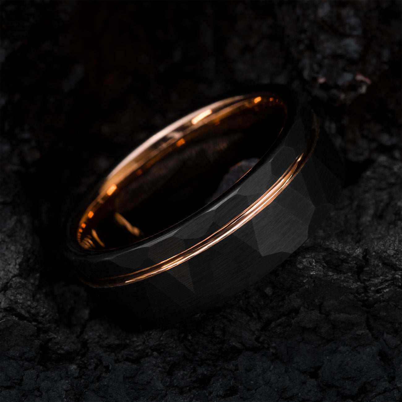 Auranel wedding band with hammered black exterior and rose gold sleeve on dark textured background