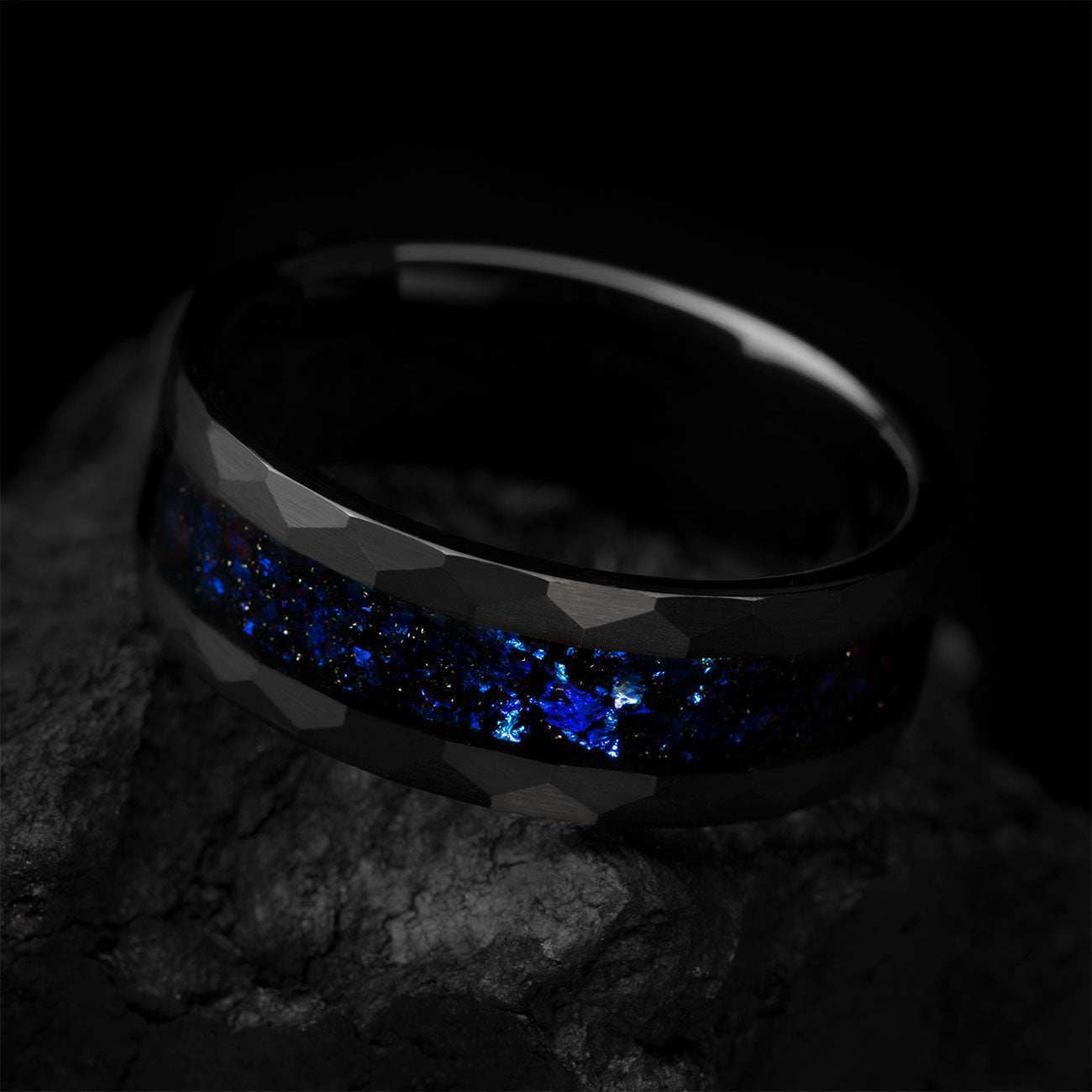 Dianviel 8mm eternity wedding band with faceted black design and blue alexandrite inlay on rock background