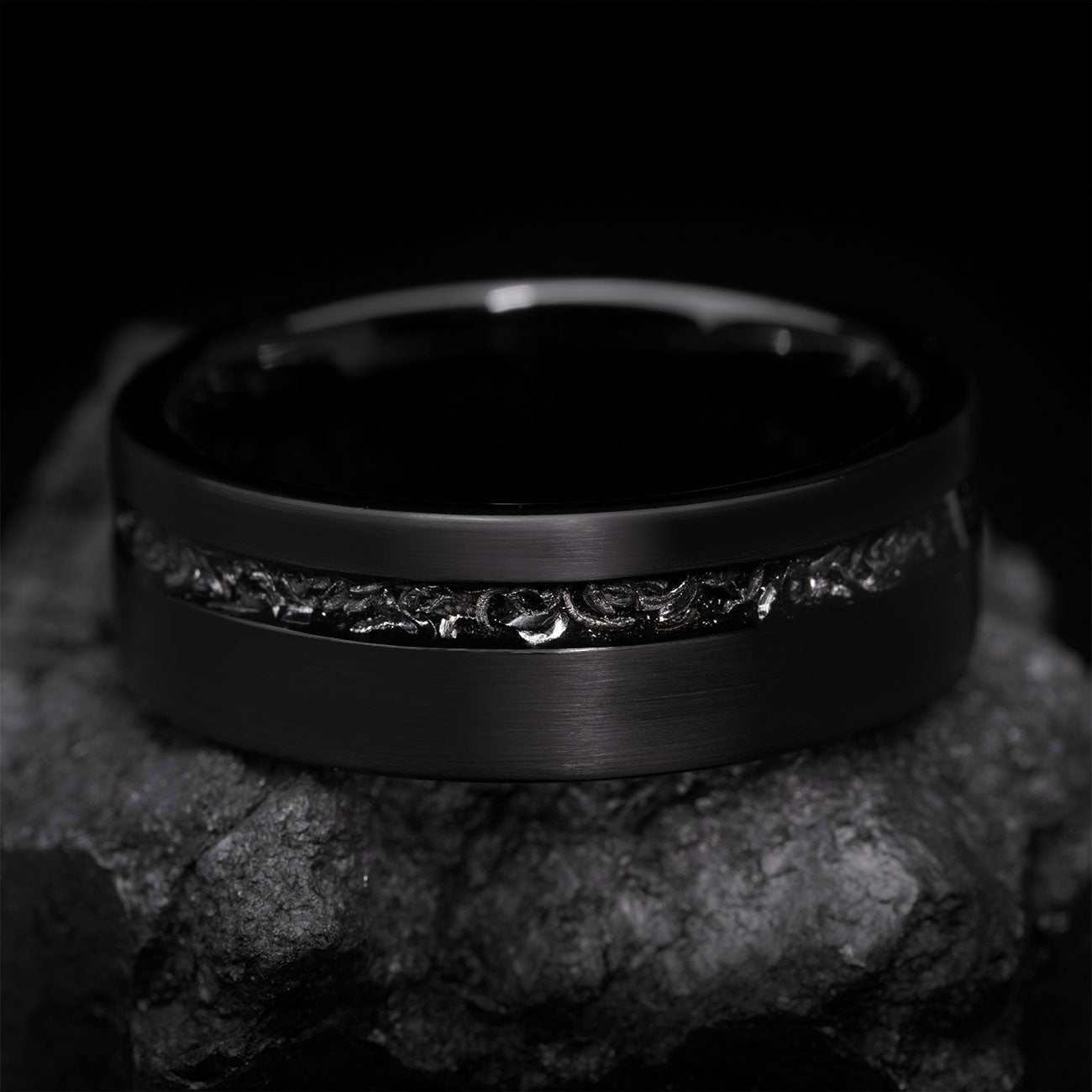 Yiloria black ring with genuine meteorite inlay and eternity design on textured stone background