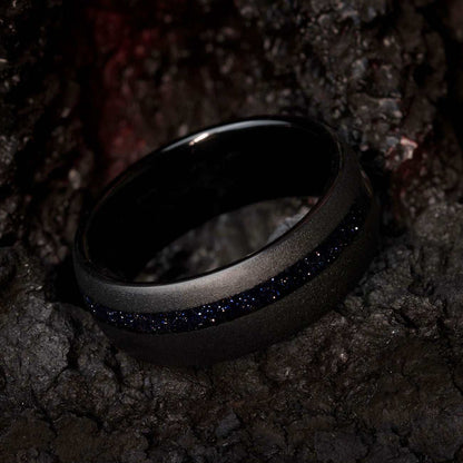 Black tungsten carbide ring with deep blue star Sandstone gemstone and sandblasted finish on dark background