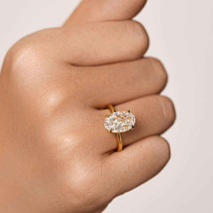 Close-up of hand wearing Pherinwen Deus Ring with oval-cut moissanite solitaire on gold band