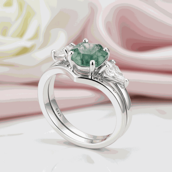 Silver ring with hexagonal moss agate center stone and kite-shaped side stones on satin background