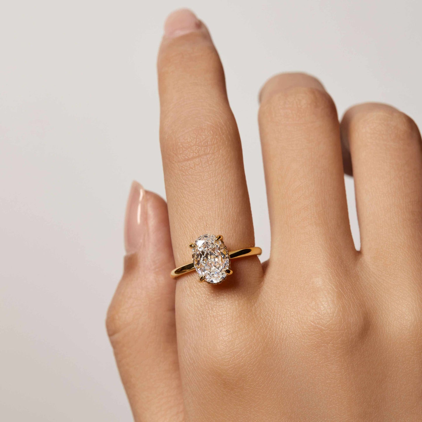 Nolindra solitaire engagement ring with oval Moissanite and pavé hidden halo on hand