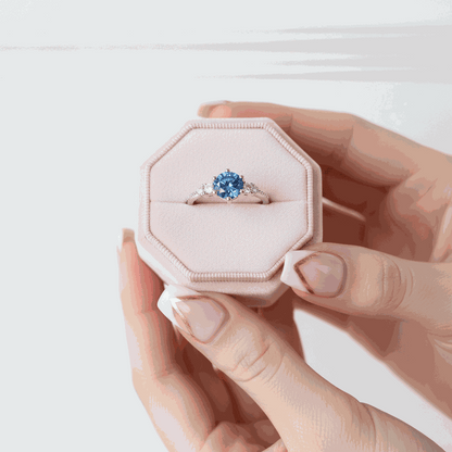 Gloraviel three-stone engagement ring with 1-carat round blue moissanite in pink ring box